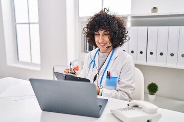 Young middle east woman wearing doctor uniform having telemedicine at clinic