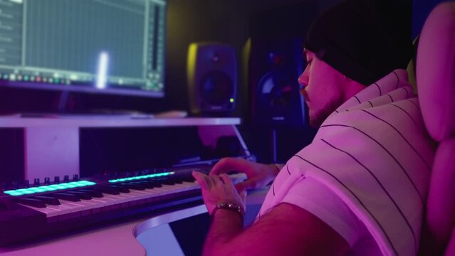 composer is creating song and working in digital audio workstation, musician is playing keyboard
