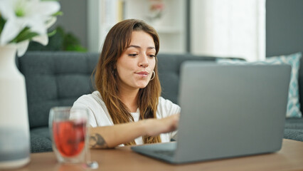 Young beautiful hispanic woman using laptop sitting on floor at home