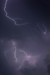 Dramatic and powerful purple lightning bolt illuminating a dark night sky