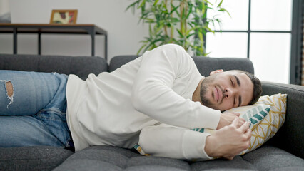 Young hispanic man lying on sofa sleeping at home