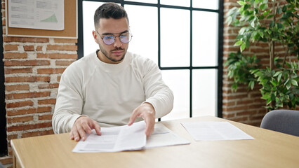 Young hispanic man business worker smiling confident holding documents at office