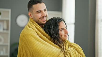 Obraz premium Man and woman couple hugging each other covering with blanket at home