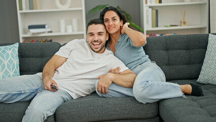 Man and woman couple hugging each other watching television at home