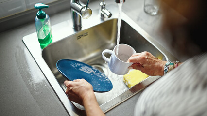Fototapeta na wymiar Middle age hispanic woman washing plates at the kitchen