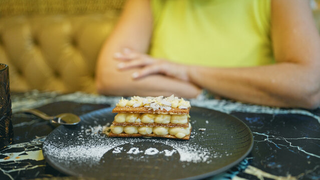 Middle age hispanic woman eating milhoja as dessert in a restaurant