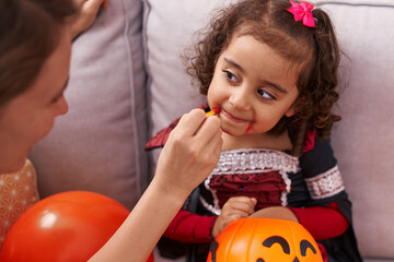 Adorable hispanic girl having halloween makeup at home