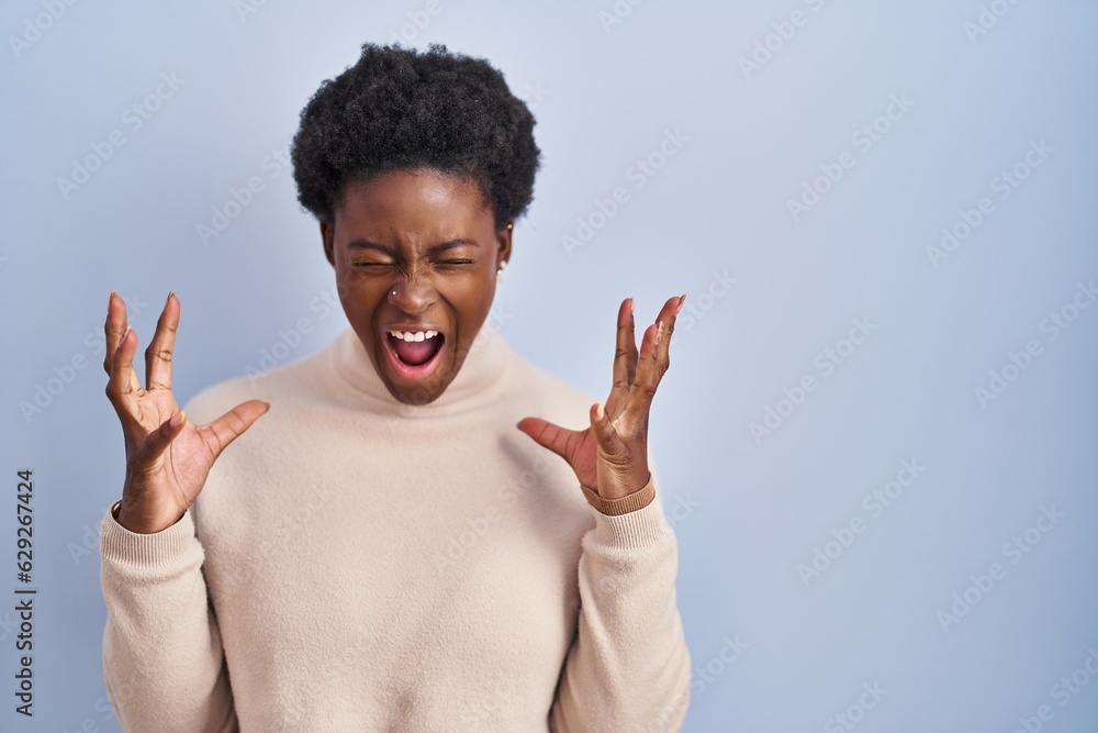 Poster African american woman standing over blue background celebrating mad and crazy for success with arms raised and closed eyes screaming excited. winner concept