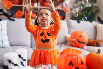 Adorable hispanic girl having halloween party playing with soap bubbles at home