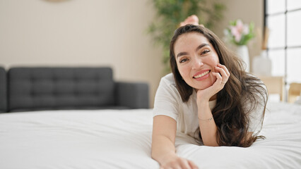 Young beautiful hispanic woman smiling confident lying on bed at bedroom