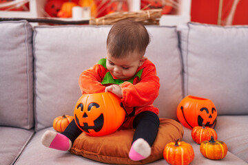 Adorable hispanic baby having halloween party wearing pumpkin costume at home