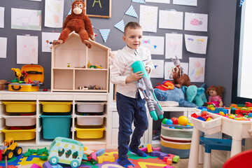 Adorable caucasian boy playing with pistol toy at kindergarten
