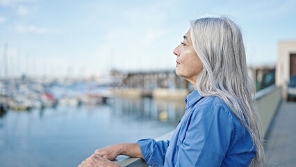 Fototapeta na wymiar Middle age grey-haired woman looking to the side with serious expression at seaside