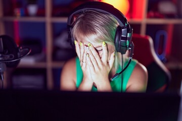Young blonde woman streamer stressed using computer at gaming room