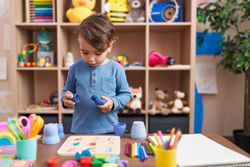 Adorable hispanic boy playing with toys standing at kindergarten
