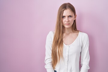 Young caucasian woman standing over pink background skeptic and nervous, frowning upset because of problem. negative person.