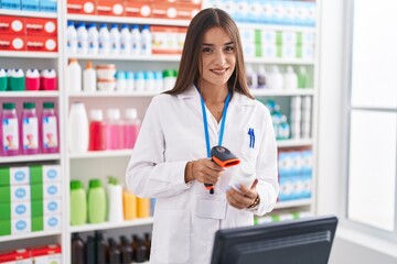 Young beautiful hispanic woman pharmacist scanning pills bottle at pharmacy