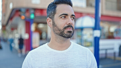 Young hispanic man looking to the side with serious expression at street