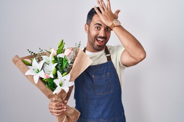 Hispanic man with beard working as florist surprised with hand on head for mistake, remember error....