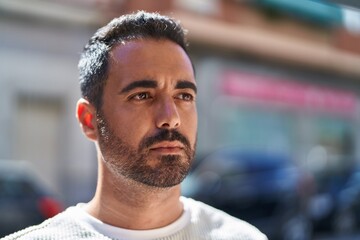 Young hispanic man with relaxed expression standing at street