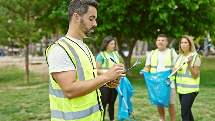 Group of people volunteers writing on clipboard at park