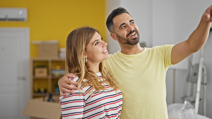 Fototapeta premium Man and woman couple hugging each other looking around at new home