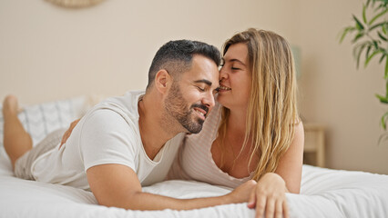 Fototapeta premium Man and woman couple lying on bed hugging each other kissing at bedroom