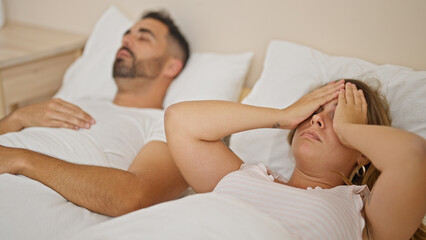 Man and woman couple lying on bed stressed for snore at bedroom