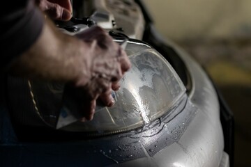 Closeup of a person placing tape on the headlights of a car in the garage