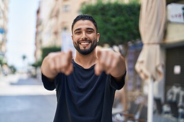 Fototapeta premium Young arab man smiling confident pointing with fingers to the camera at street