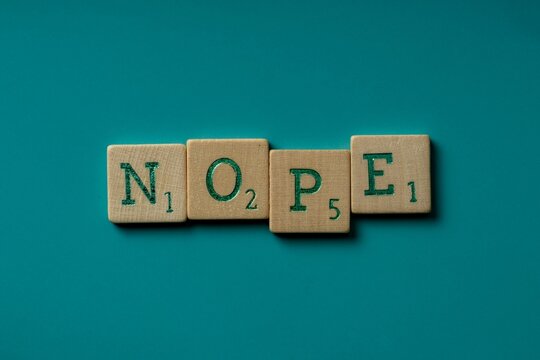 Wooden letters spelling the word "nope" on a blue background