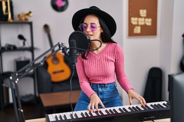 Young caucasian woman musician singing song playing piano at music studio