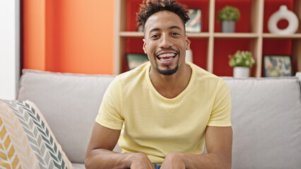 African american man smiling confident sitting on sofa speaking at home