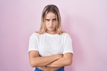 Young blonde woman standing over pink background skeptic and nervous, disapproving expression on...