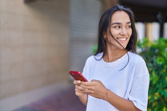 Young beautiful hispanic woman smiling confident using smartphone at street
