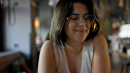 Young beautiful hispanic woman smiling sitting on the table at the restaurant