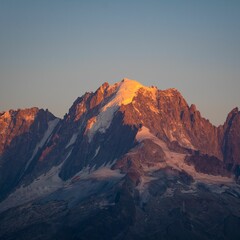 Fototapeta na wymiar Striking view of a snow-capped mountain illuminated by the fading golden light of a setting sun