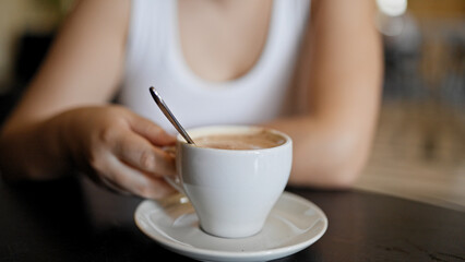 Young beautiful hispanic woman drinking coffee sitting on the table at cafeteria