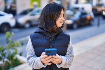 Young woman with down syndrome smiling confident using smartphone at street