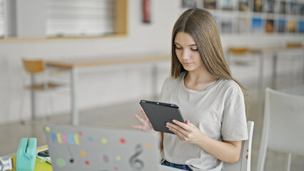 Young beautiful girl student using laptop and touchpad studying at library