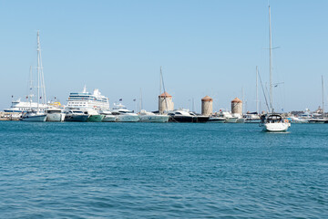 Naklejka premium selective focus on Mandraki harbor with passenger boats and old windmills near Fort Saint Nicholas