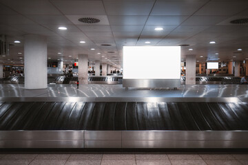 Lisbon; Luggage claim area; A conveyor belt featuring a white blank mockup in the back. The grey-toned surroundings are impeccably illuminated with bright white lights