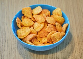 Wooden table with a blue bowl full of potato chips