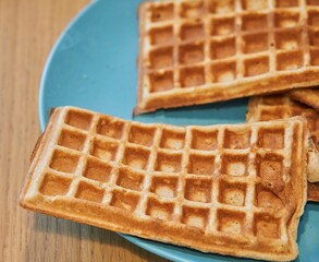 Plate of freshly-made waffles sitting atop a wooden table.