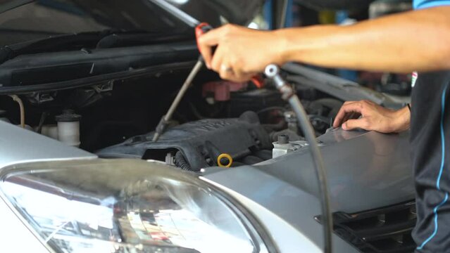 Auto mechanic hand using blower to remove dust in engine compartment