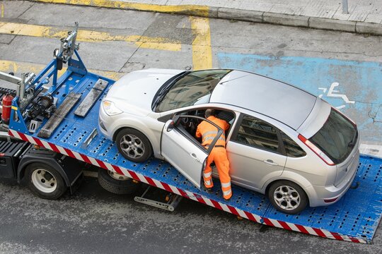 Roadside assistance concept. Damaged car being loaded onto tow truck by a worker