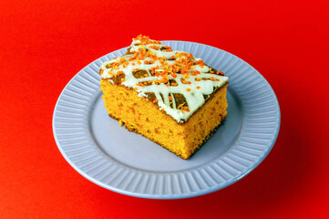 slice of carrot cake with white cream on a red background