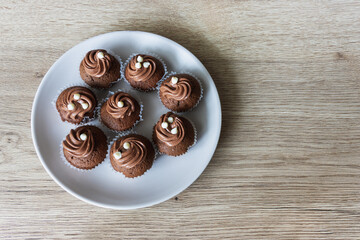 Mini chocolate cupcakes on a plate on an oak table