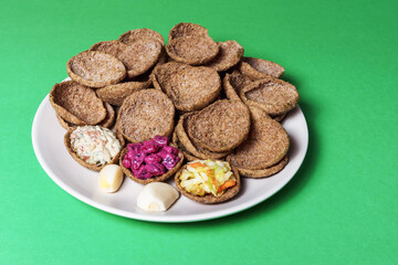 Rye bread toasts on a plate on a green background