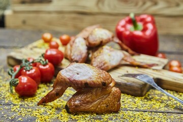 Smoked chicken wings surrounded by vegetables. Breakfast products. Meat production